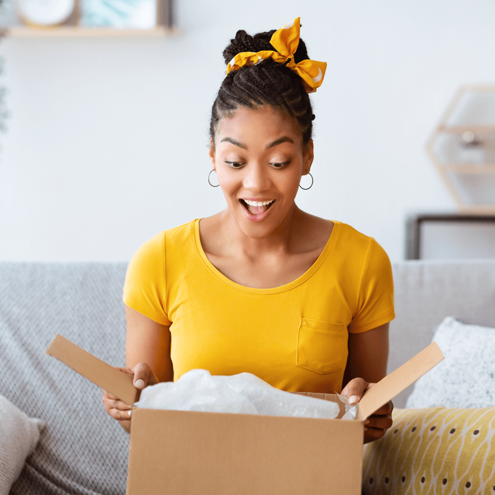 surprised young woman opening a shipping box