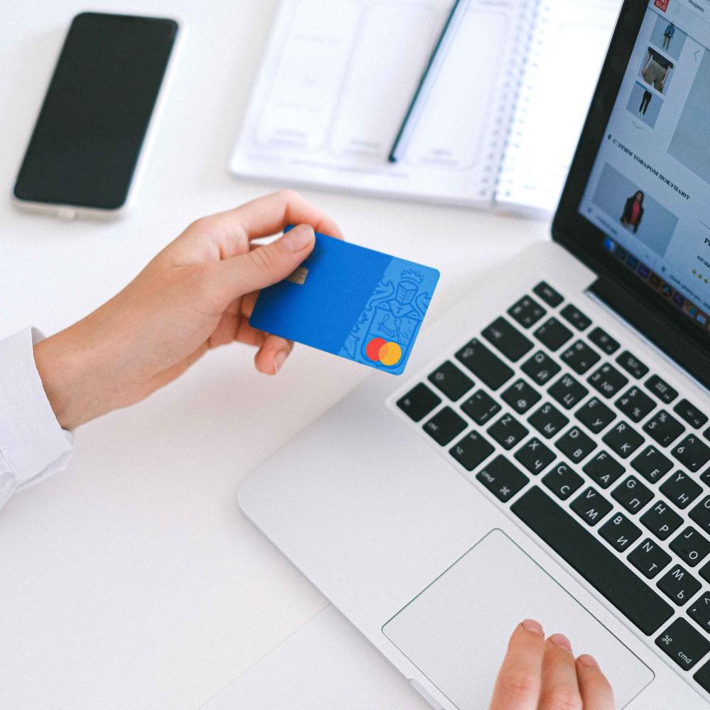 En person bruger sit betalingskort til at betale i en webshop på sin computer