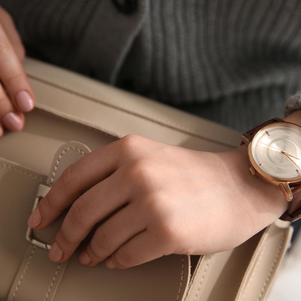 woman wearing high end watch opening designer hand bag