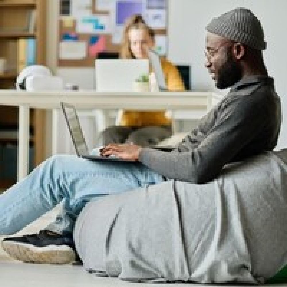 Man sitting on a bean bag chair using laptop