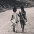 Two girls walking down a dirt road
